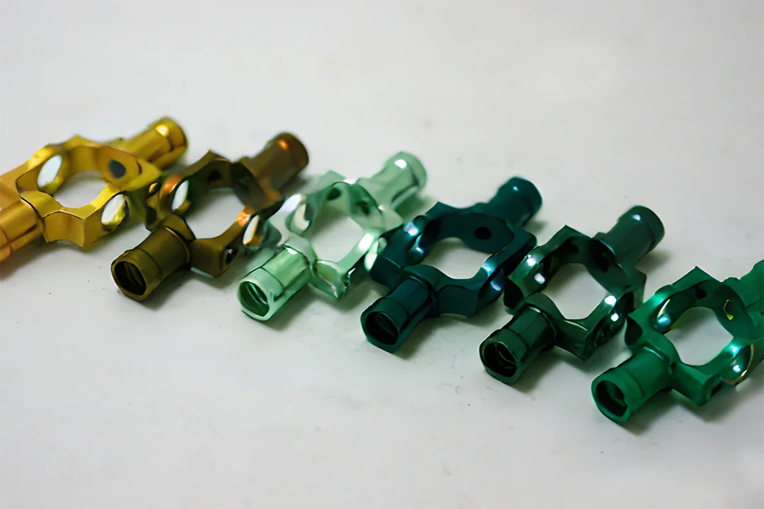 Anodized aluminum connectors are arranged in a gradient from gold to green, showcasing the detailed engineering and colors.